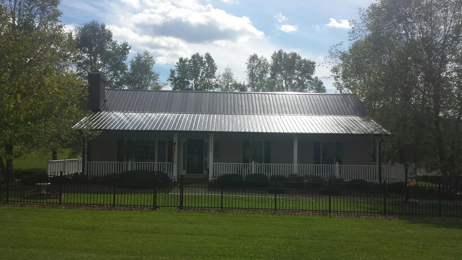 Gray metal roof on a brick ranch with a full width front porch — Gutter Guard Installation work by our crew in Crossville